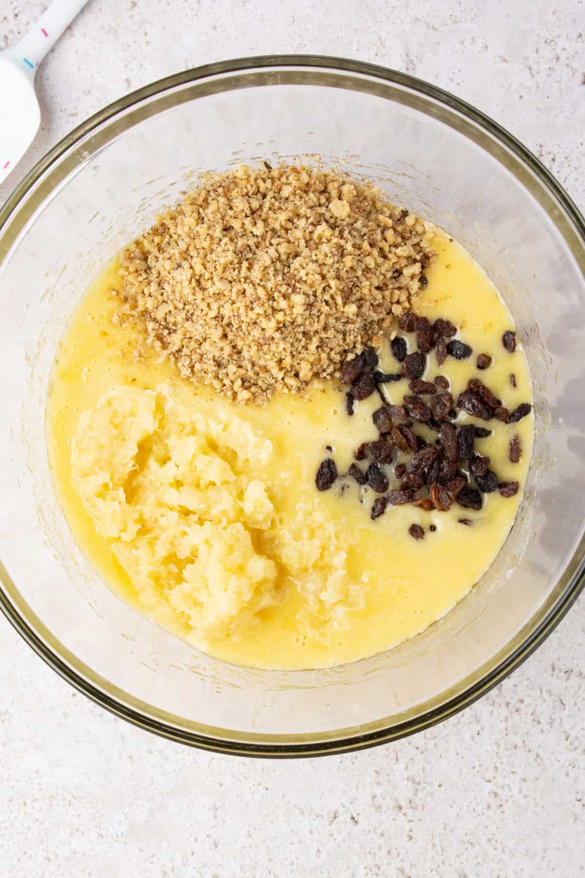 Adding pineapple, chopped nuts, and raisins to zucchini bread batter.