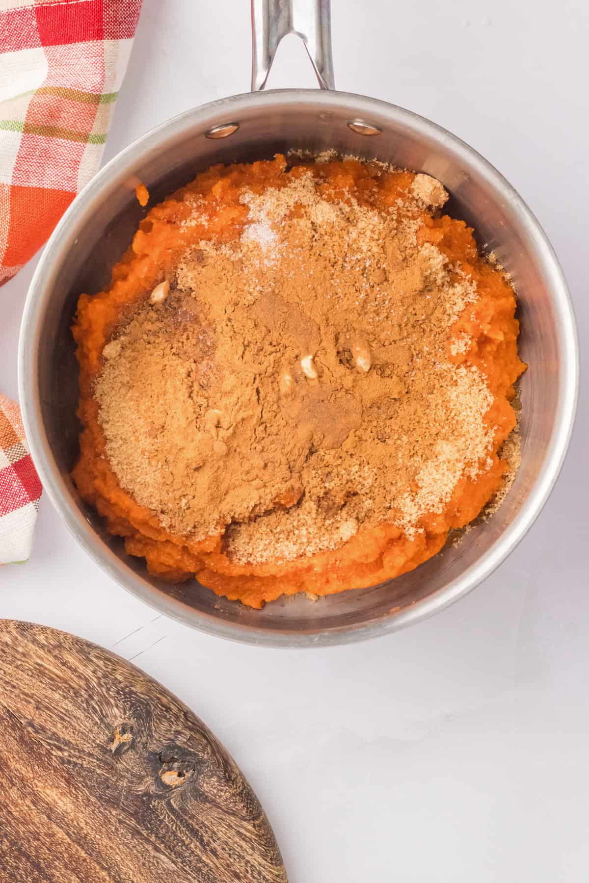 Combining ingredients for making pumpkin butter in a saucepan.