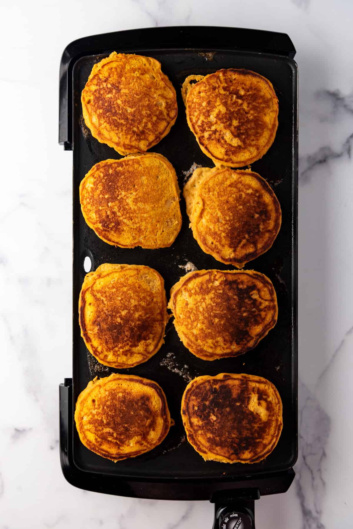 Flipped pumpkin pancakes on a griddle.