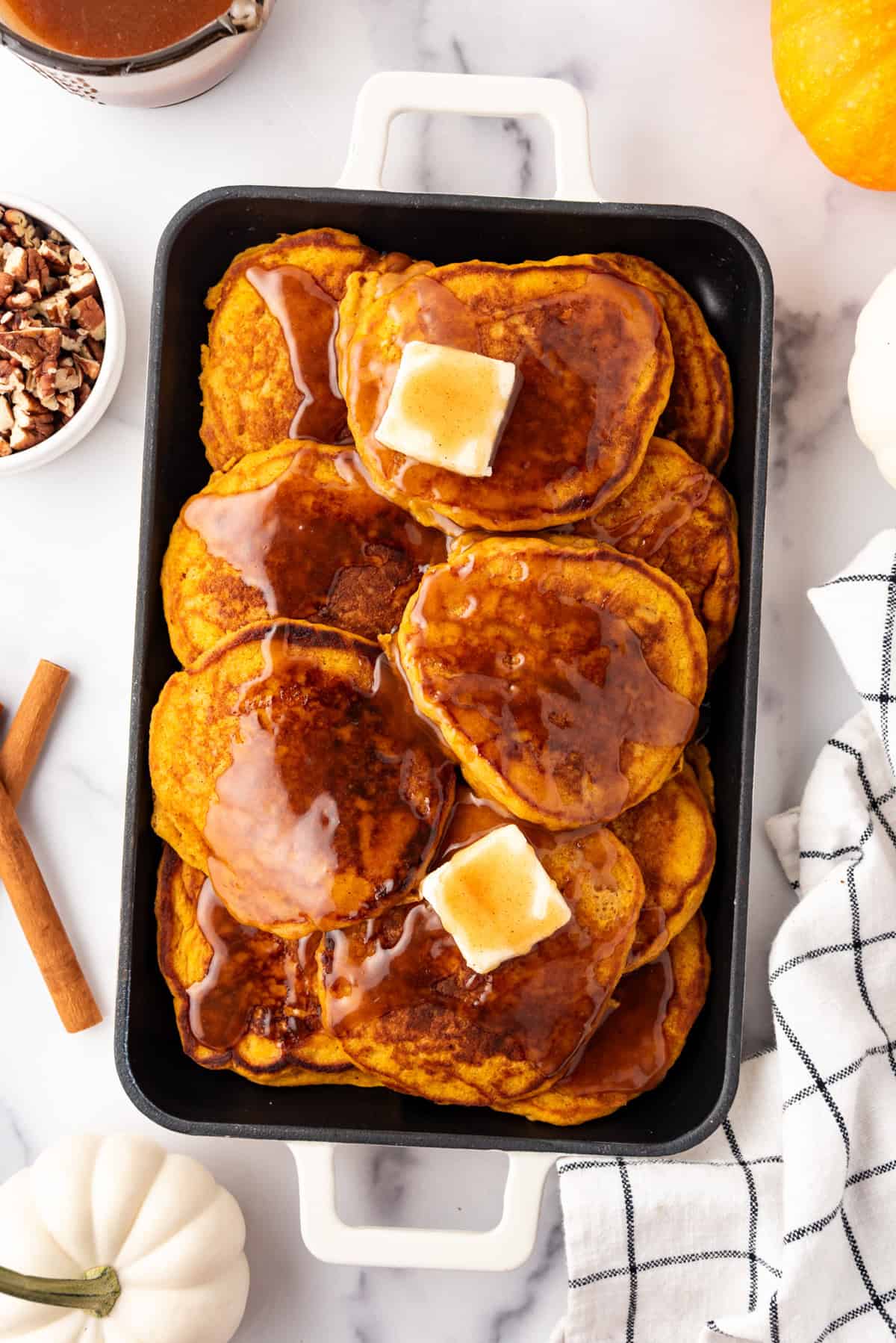 An image of pumpkin pancakes with creamy cinnamon syrup and pats of butter on top.