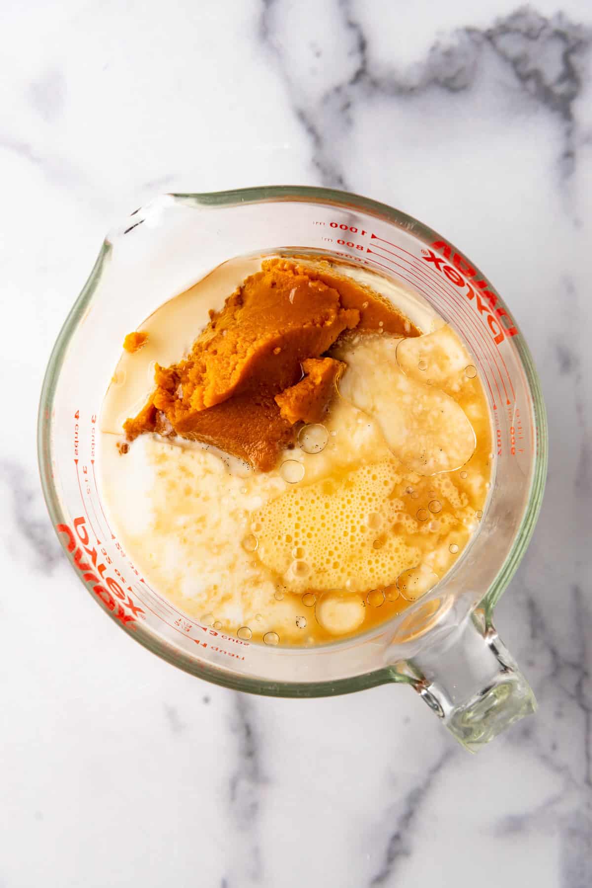 Combining wet ingredients for pumpkin pancakes in a bowl.