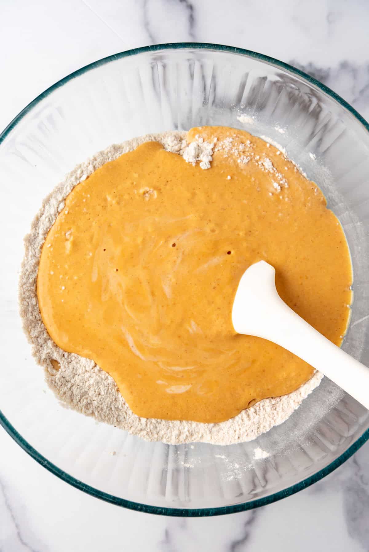 Adding wet ingredients to make pumpkin pancake batter.