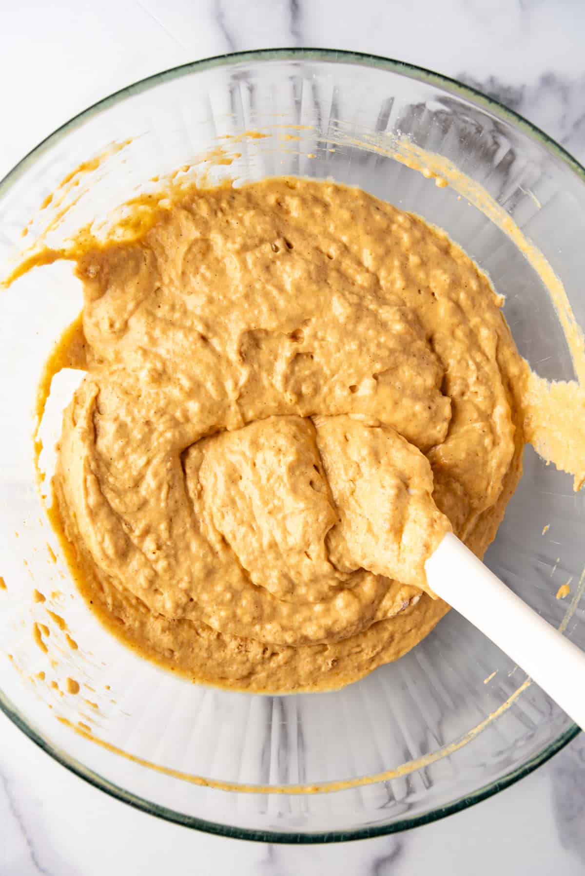 Pumpkin pancake batter in a large bowl with a spatula.