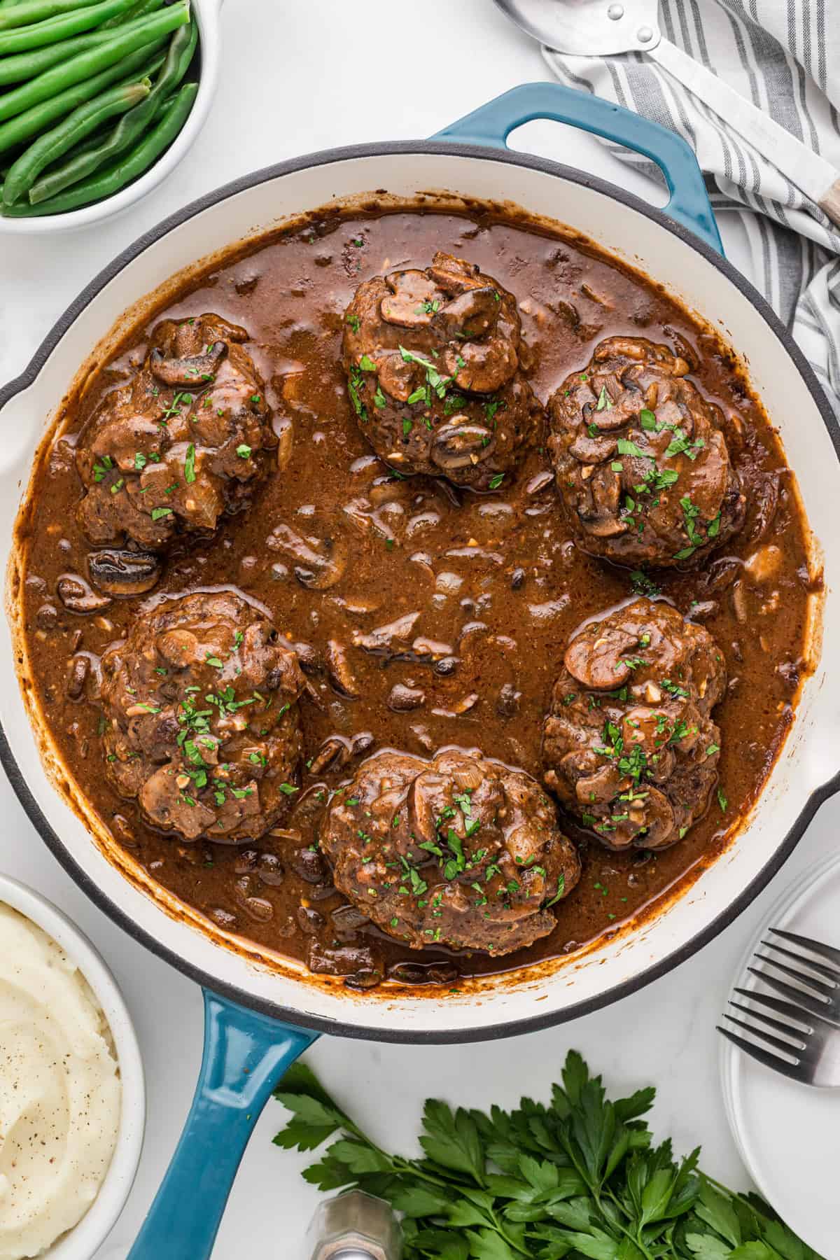 An overhead image of a pan of salisbury steak in a mushroom sauce.