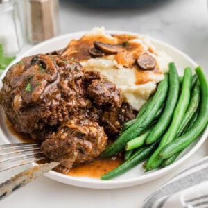 Salisbury steak on a plate with mashed potatoes and green beans.