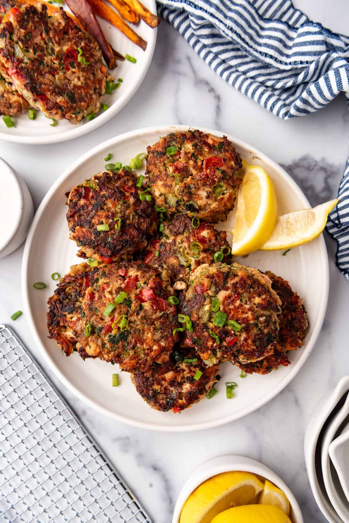 Salmon cakes on a white plate with lemon wedges in the background.