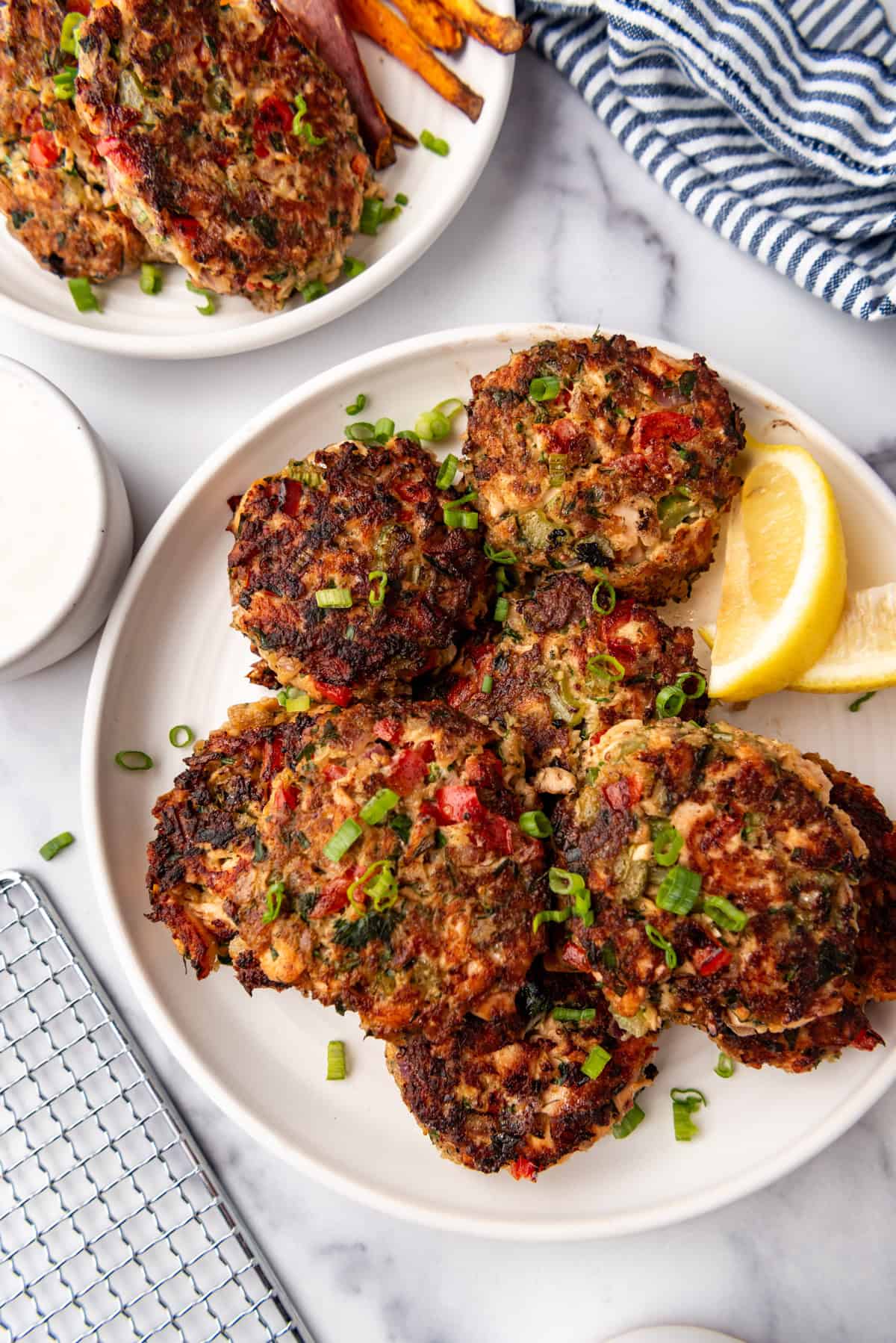 Salmon cakes on a white plate with lemon wedges in the background.