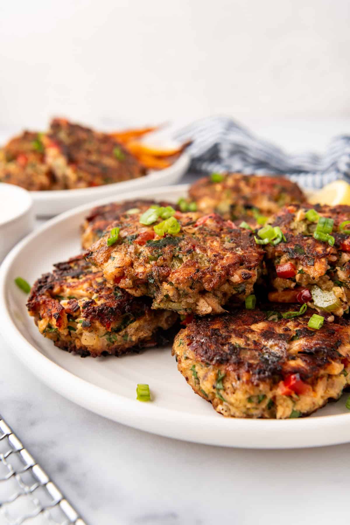 Salmon cakes on a white plate with lemon wedges in the background.