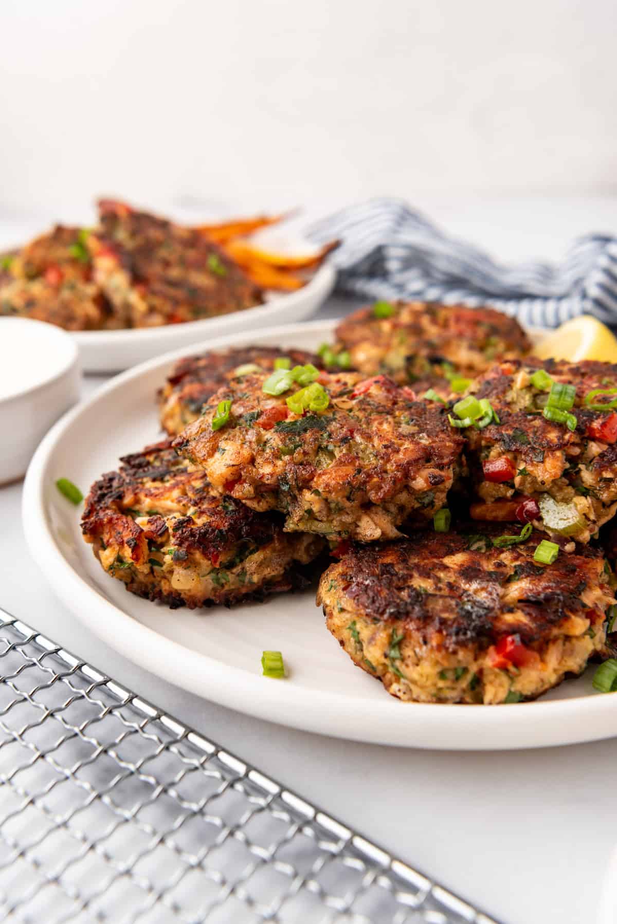 Salmon cakes on a white plate with lemon wedges in the background.