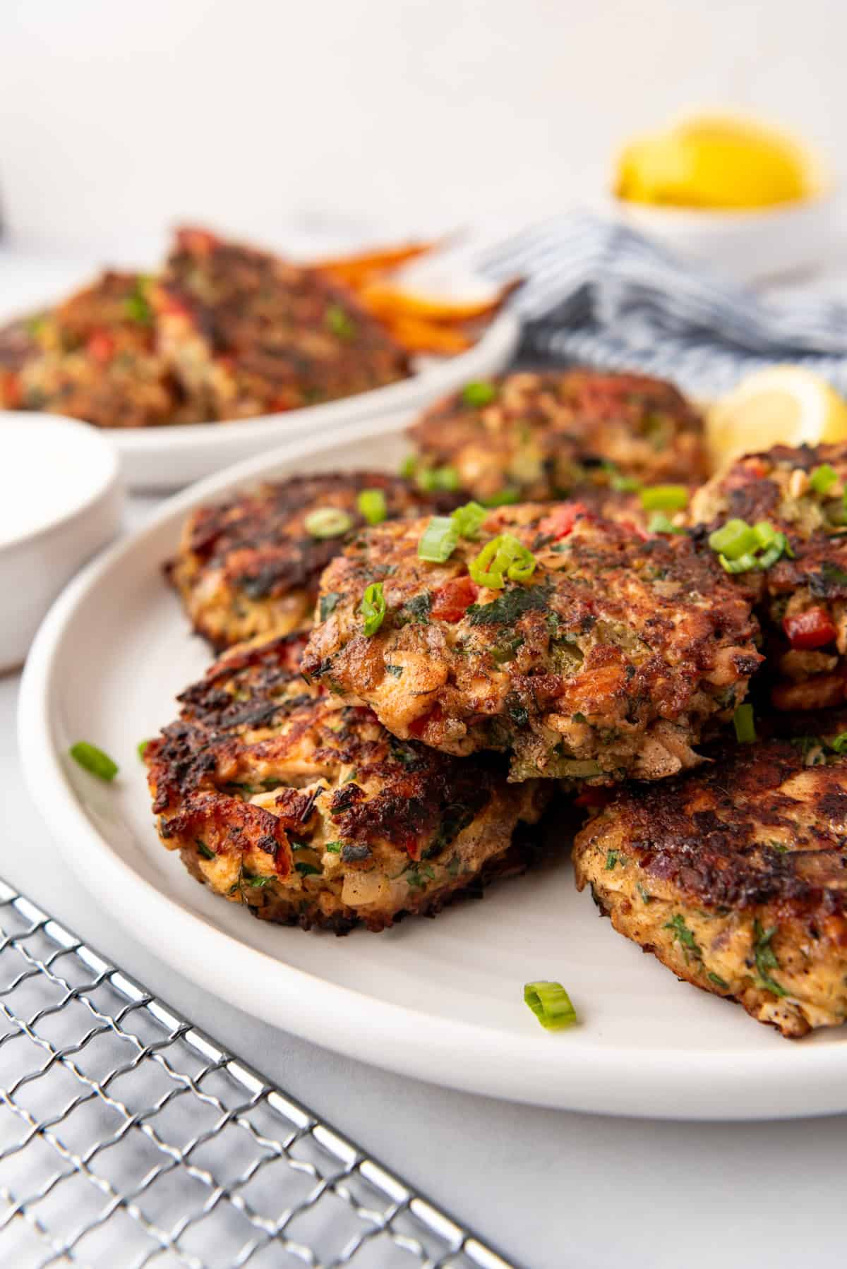 Salmon cakes on a white plate with lemon wedges in the background.