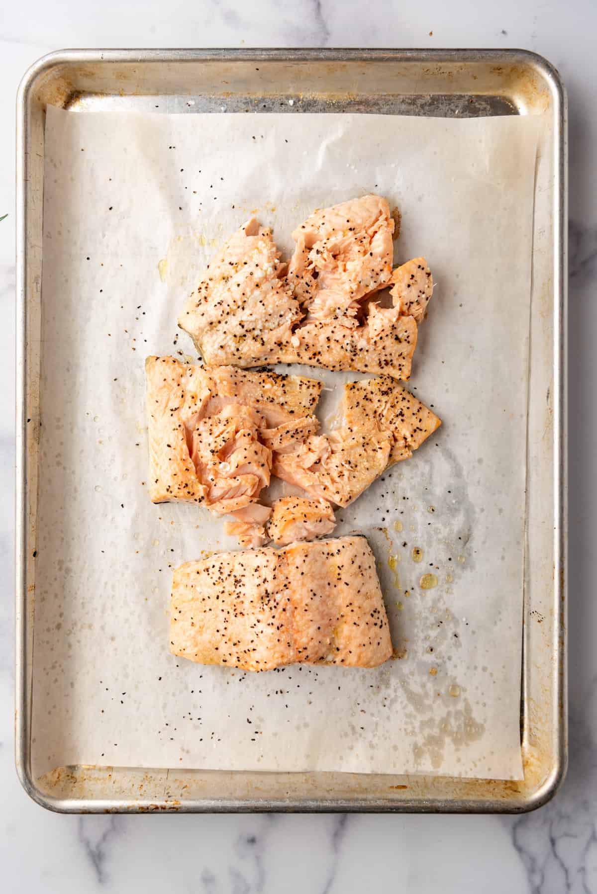 Cooked salmon on a baking sheet lined with parchment paper.