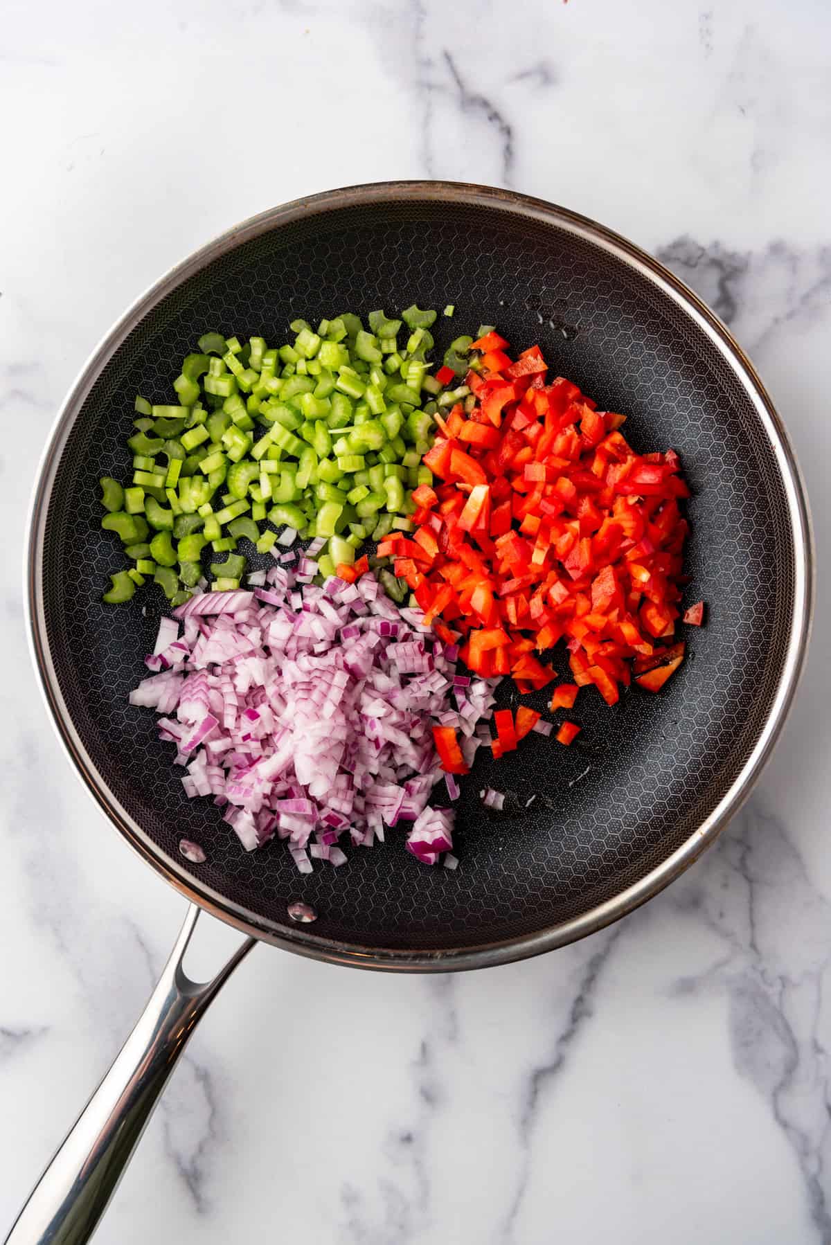 Diced green and red bell pepper and red onion in a skillet.