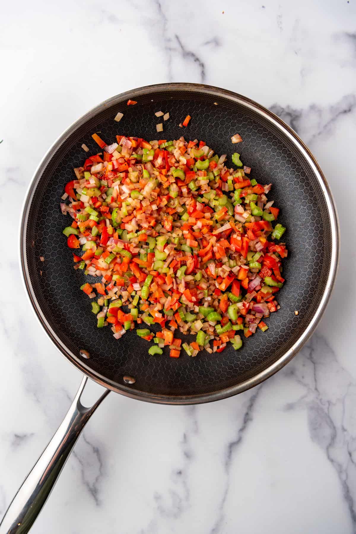 Diced and sauted green and red bell pepper and red onion in a skillet.