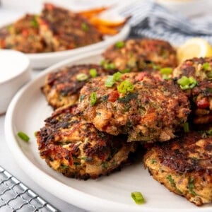 Salmon cakes on a white plate with lemon wedges in the background.