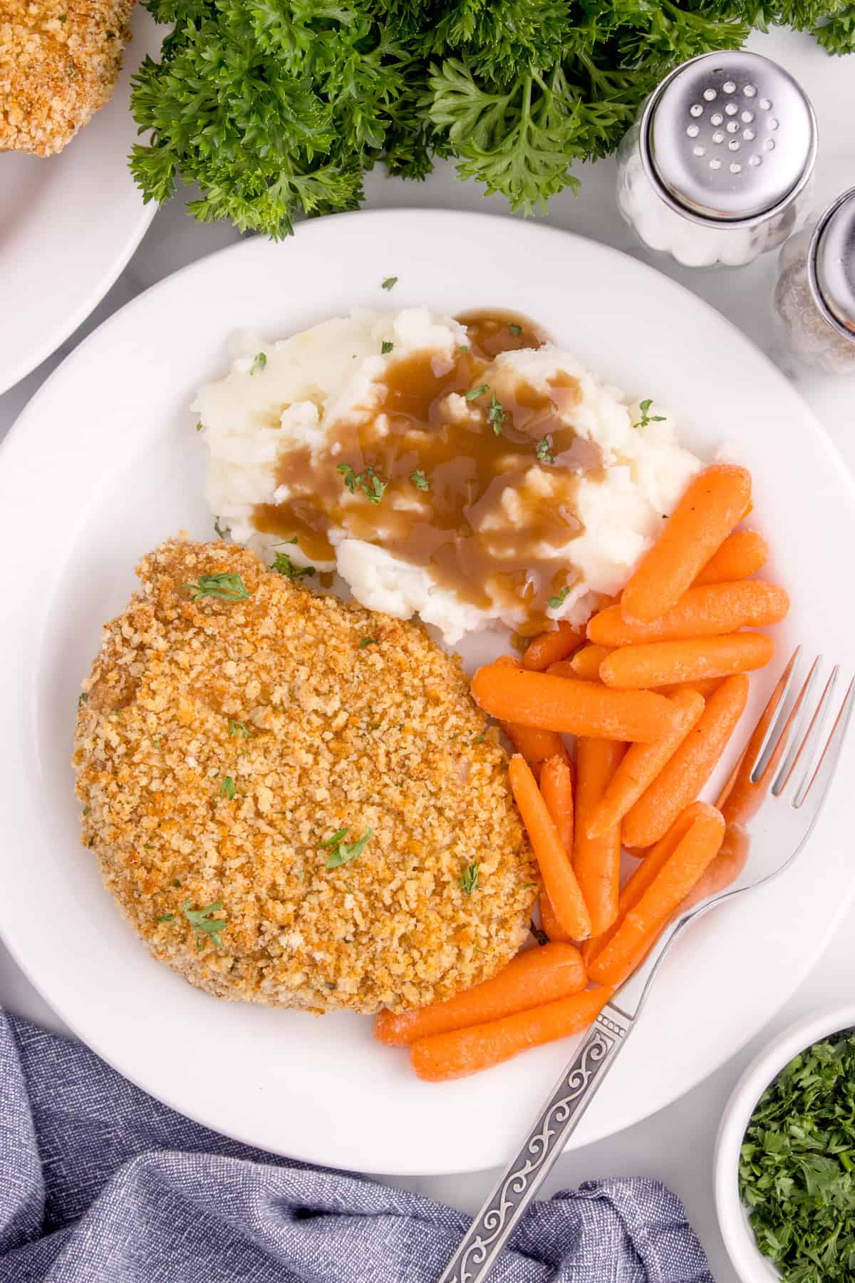 An overhead image of a pork chop dinner on a white plate.