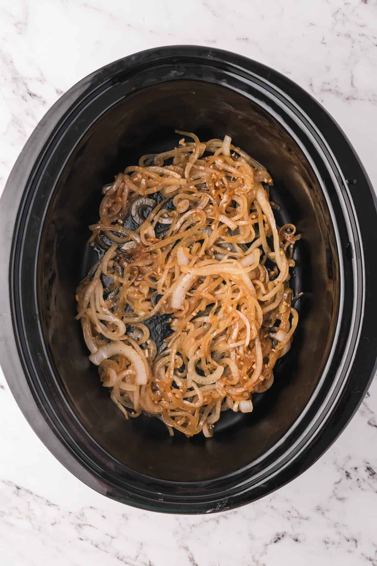 Adding sauteed onions to a slow cooker.