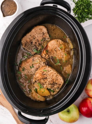 An image of slow cooker apple pork chops in the slow cooker.