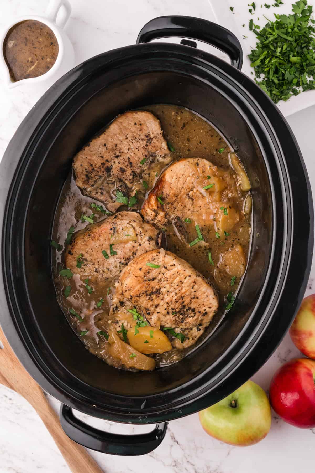 An image of slow cooker apple pork chops in the slow cooker.