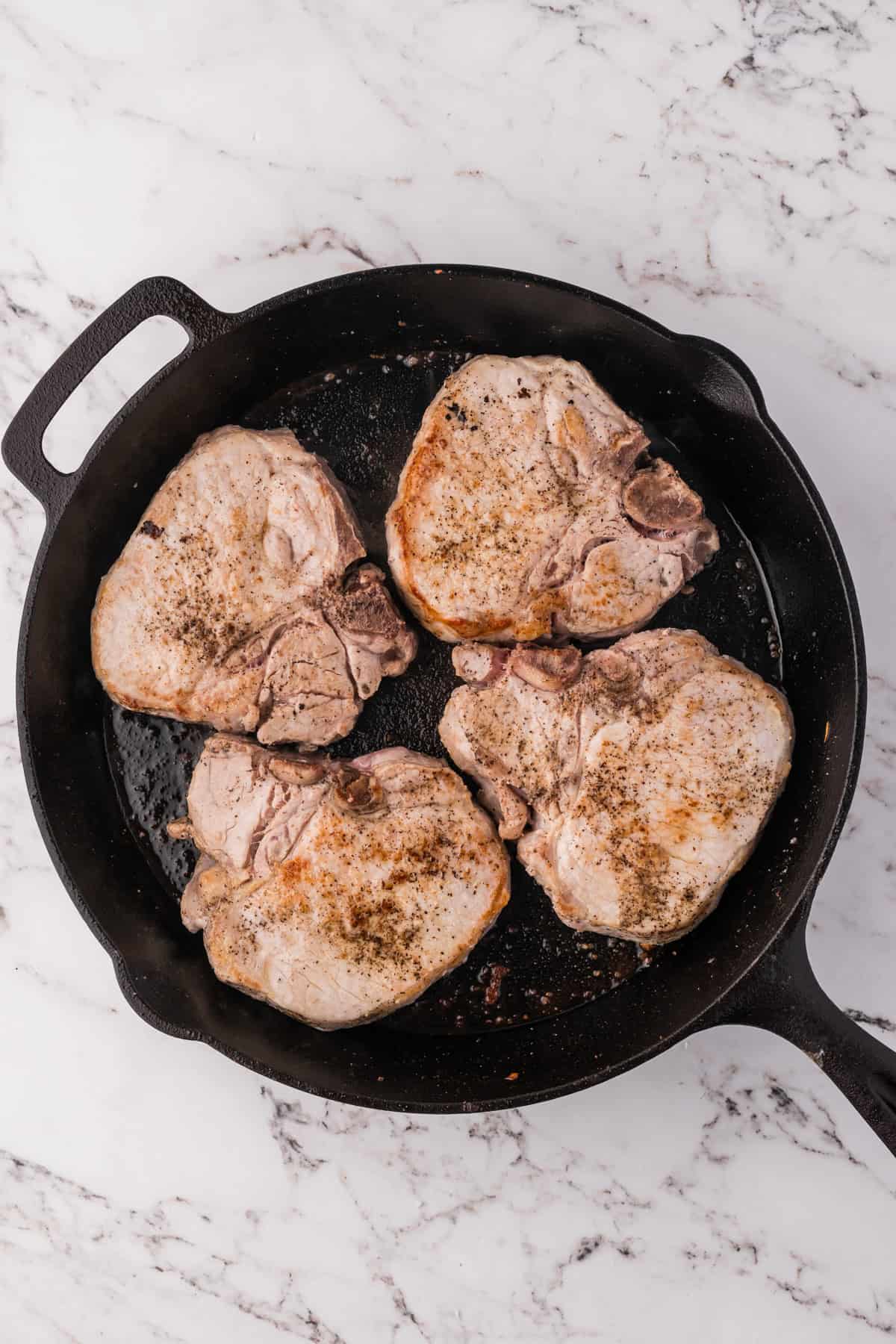 Searing pork chops in a cast iron skillet.