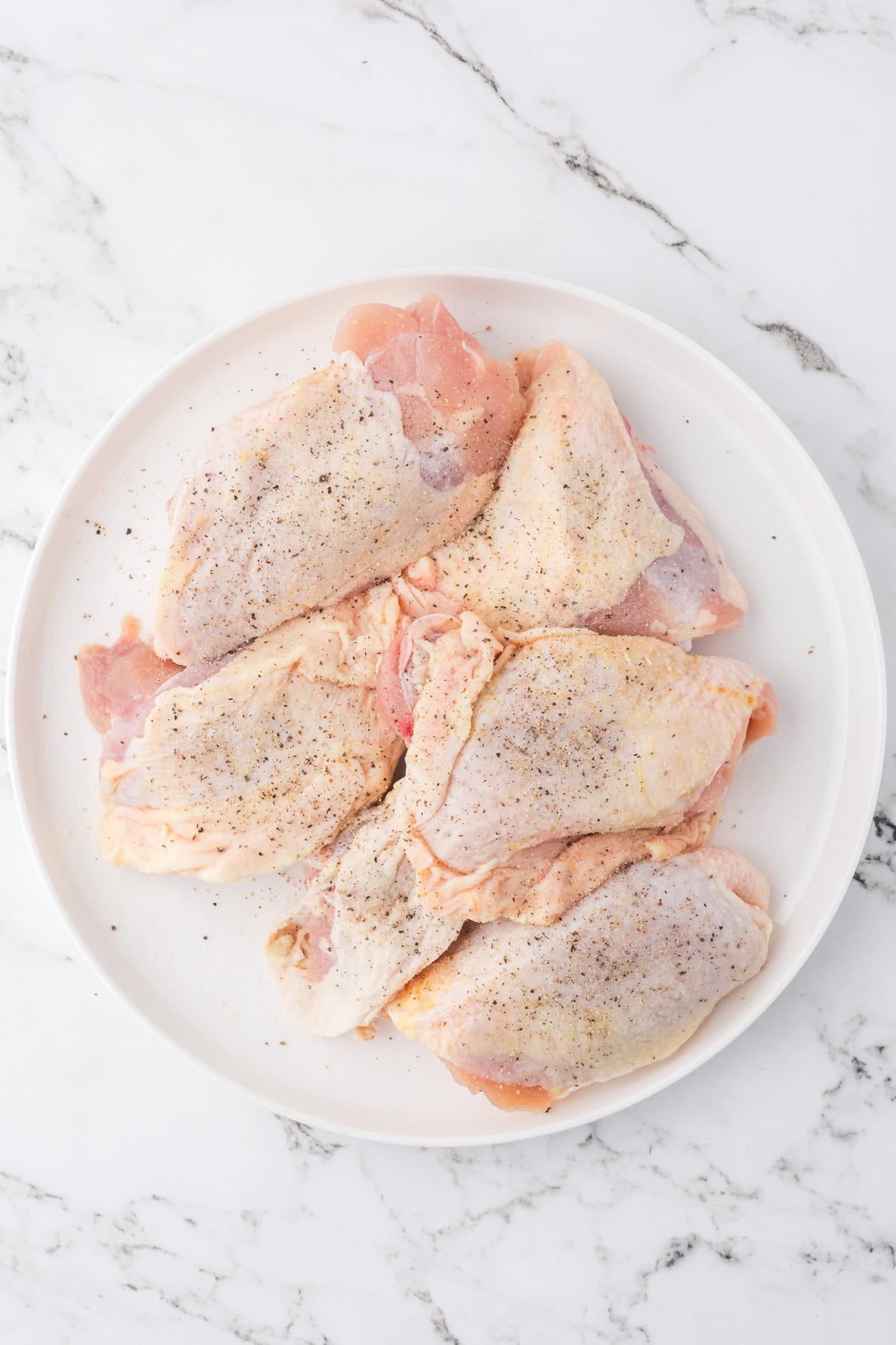 Seasoned chicken thighs on a plate.