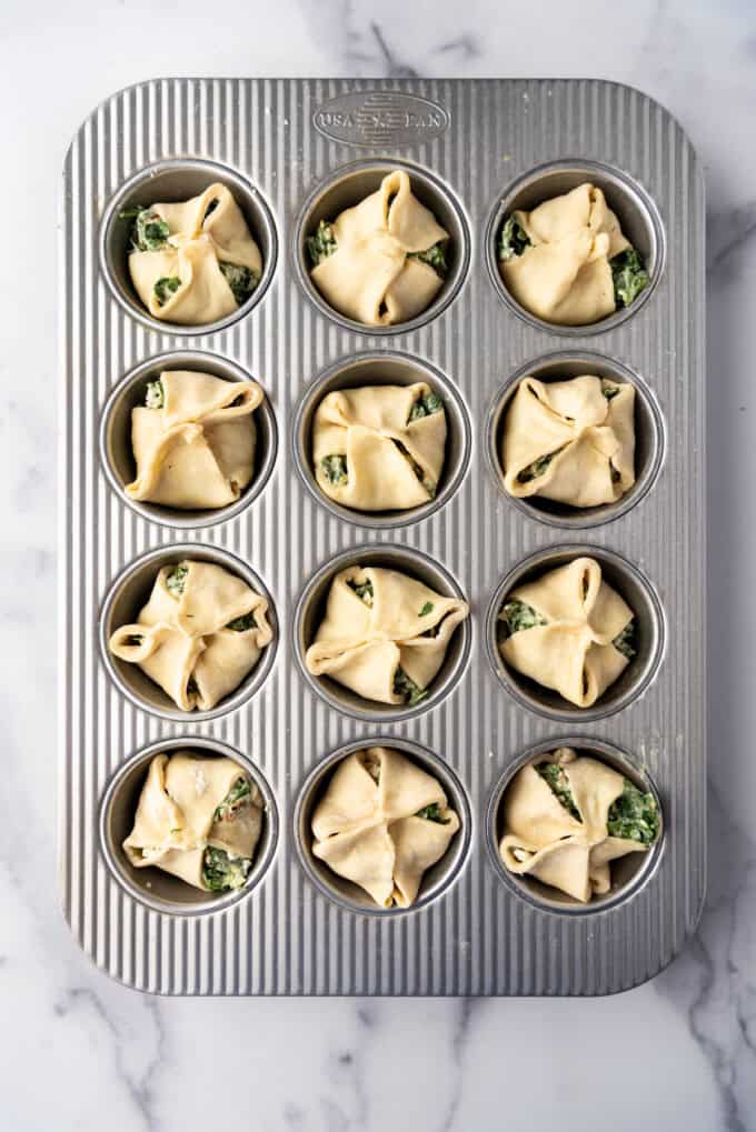 Spinach puffs in a muffin pan before baking them.