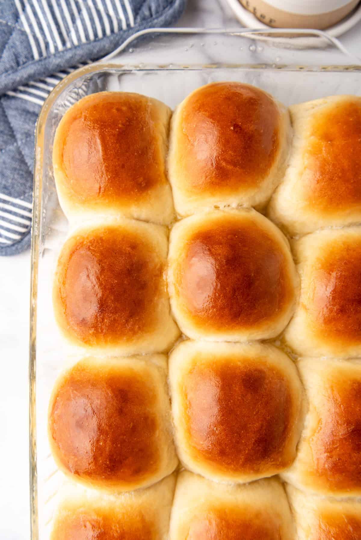 A close image of freshly baked dinner rolls with buttered tops.