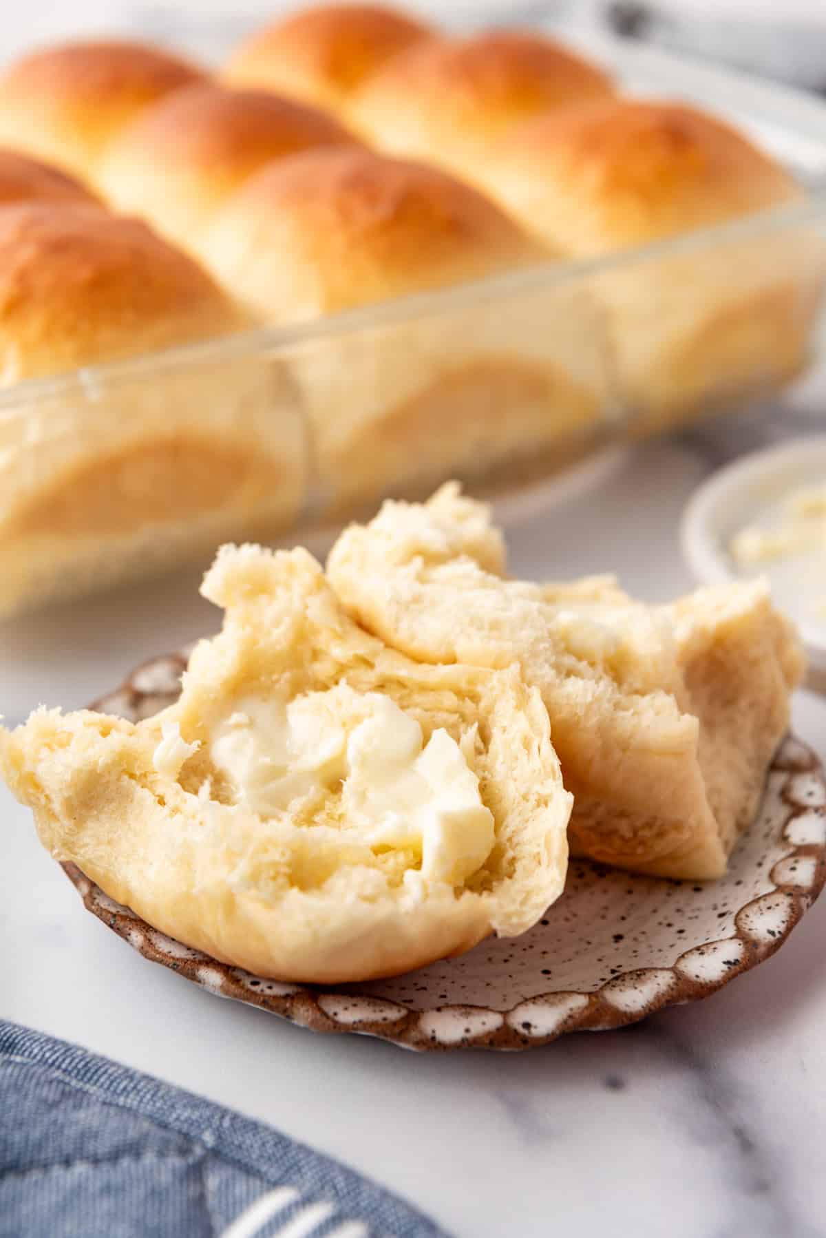 A split roll with butter on it on a plate.