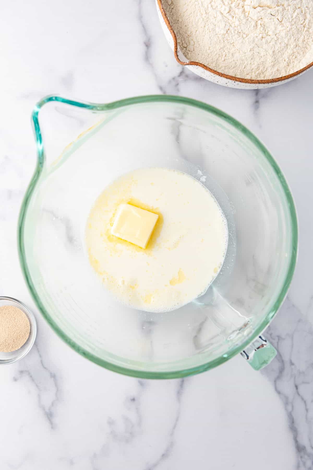 Combining warm milk and butter in a mixing bowl.