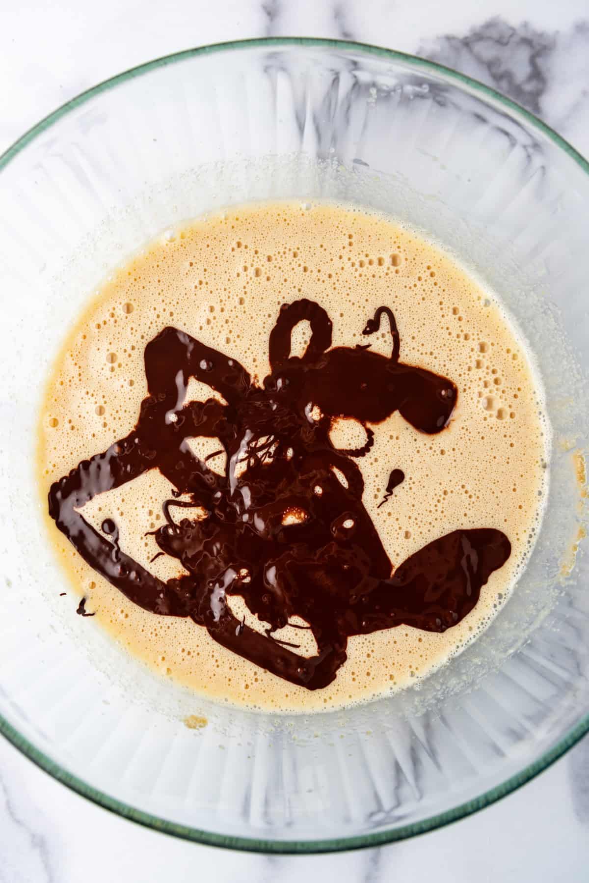 Top view of melted chocolate being added to wet ingredients for zucchini bread.