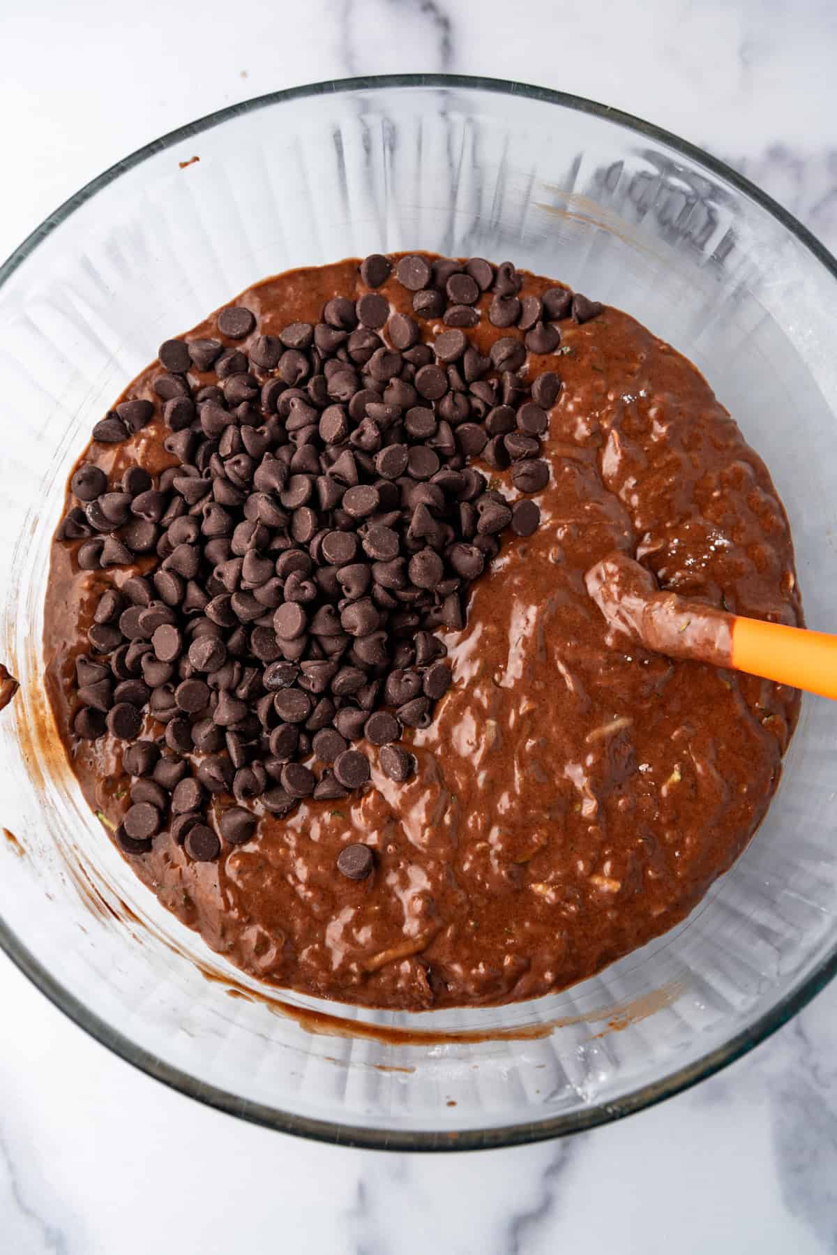 Top view of chocolate chips added to zuccini bread batter in a mixing bowl.