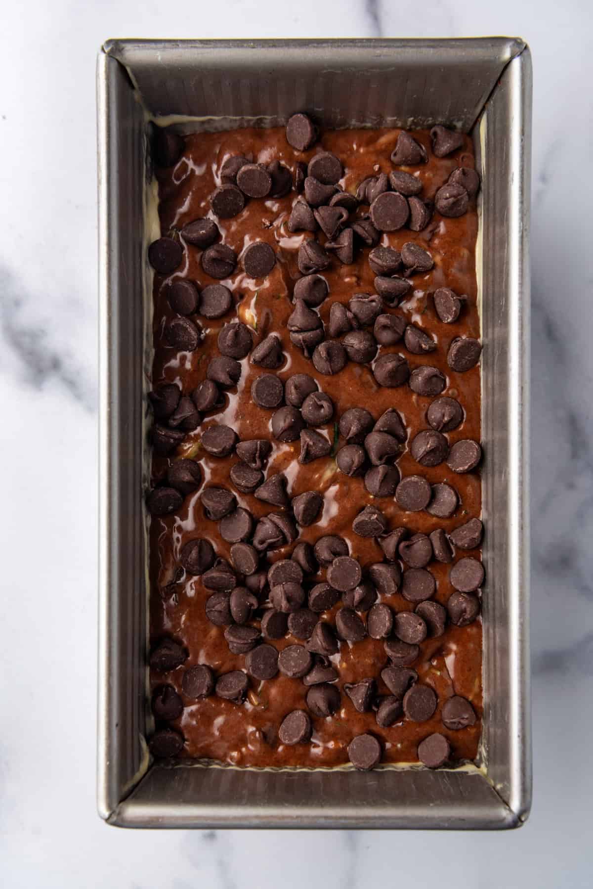 Top view of zucchini bread batter in a loaf pan, topped with chocolate chips, ready to be baked.