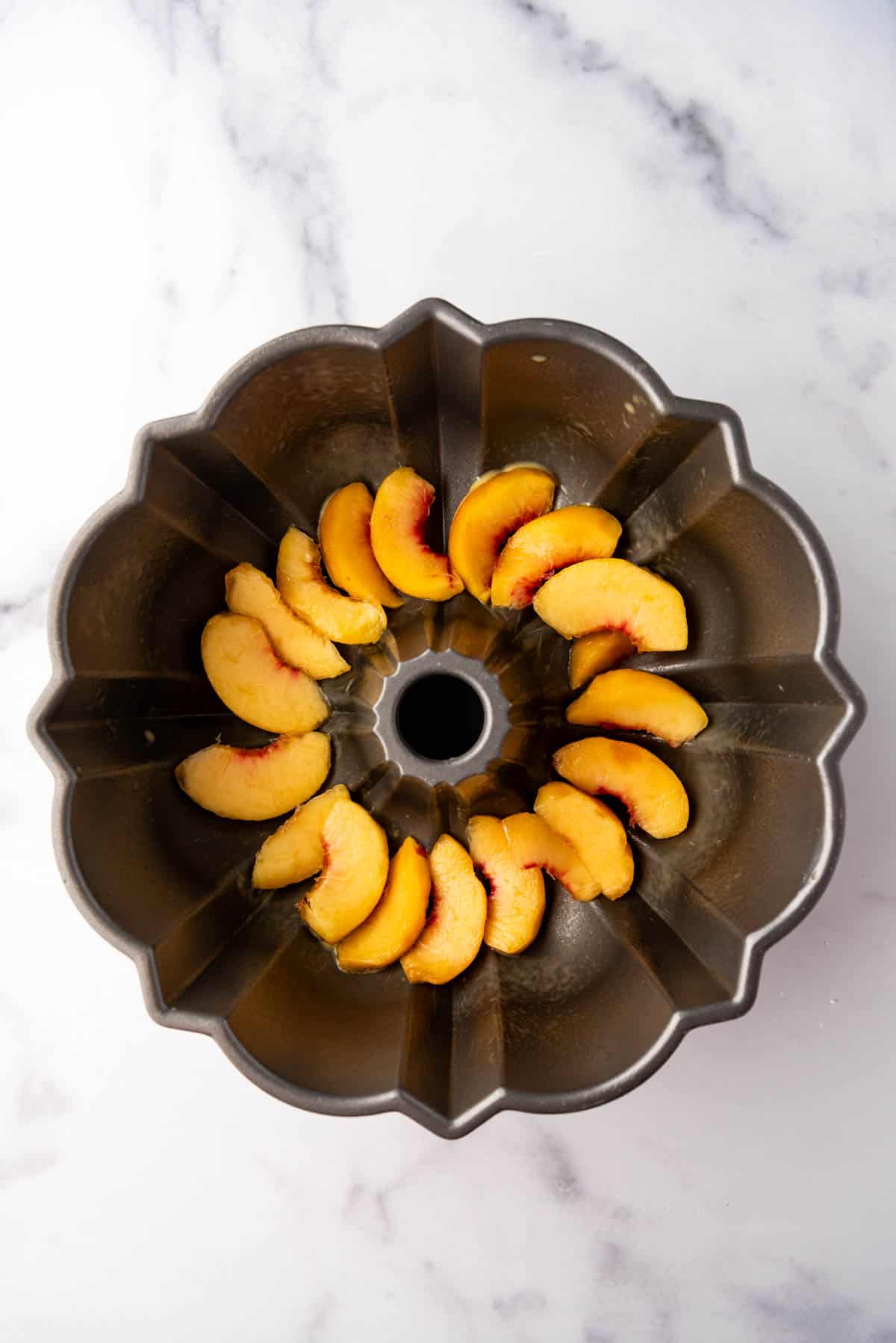 Sliced peaches in a bundt pan.