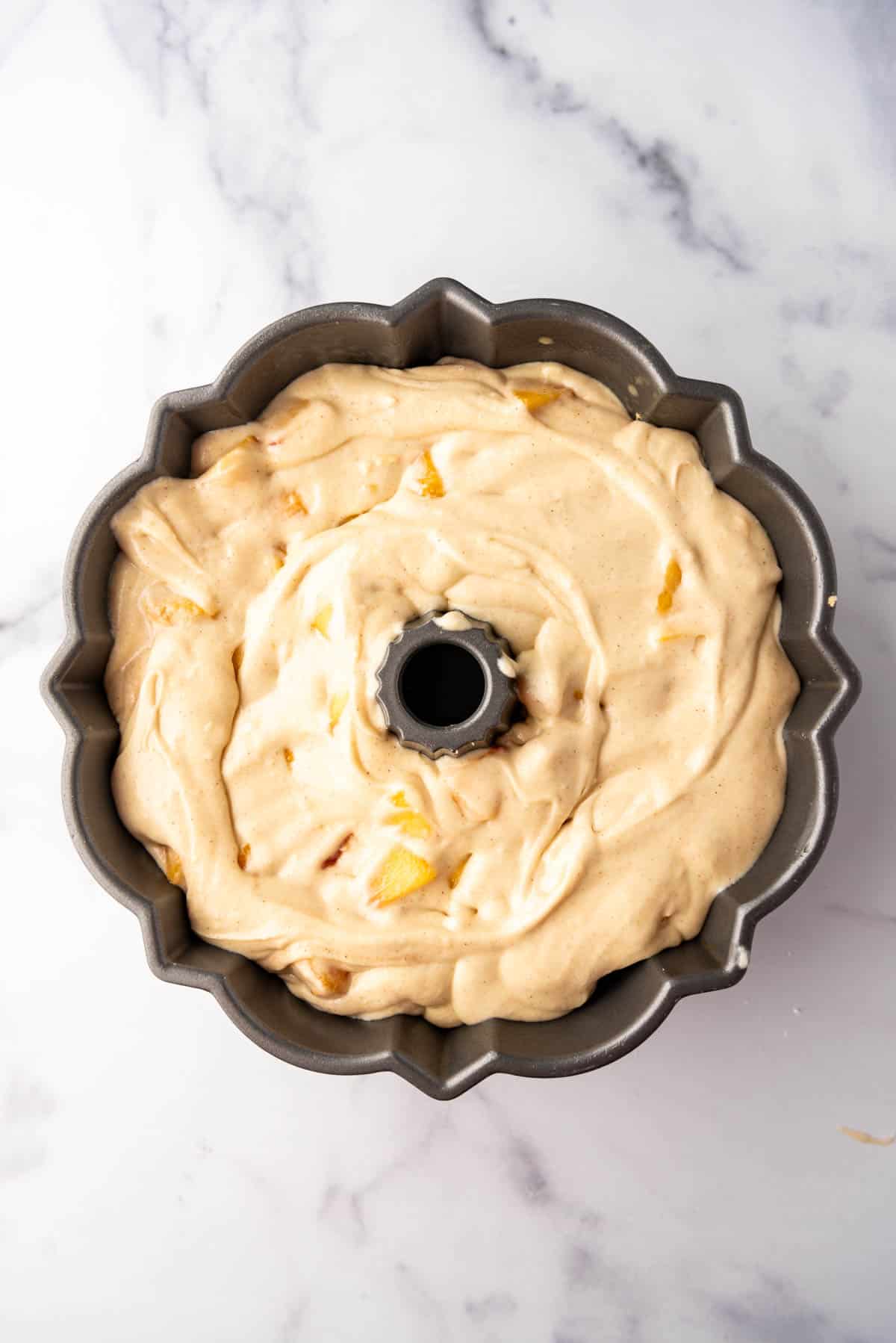 A peach cobbler pound cake in a bundt pan before baking.