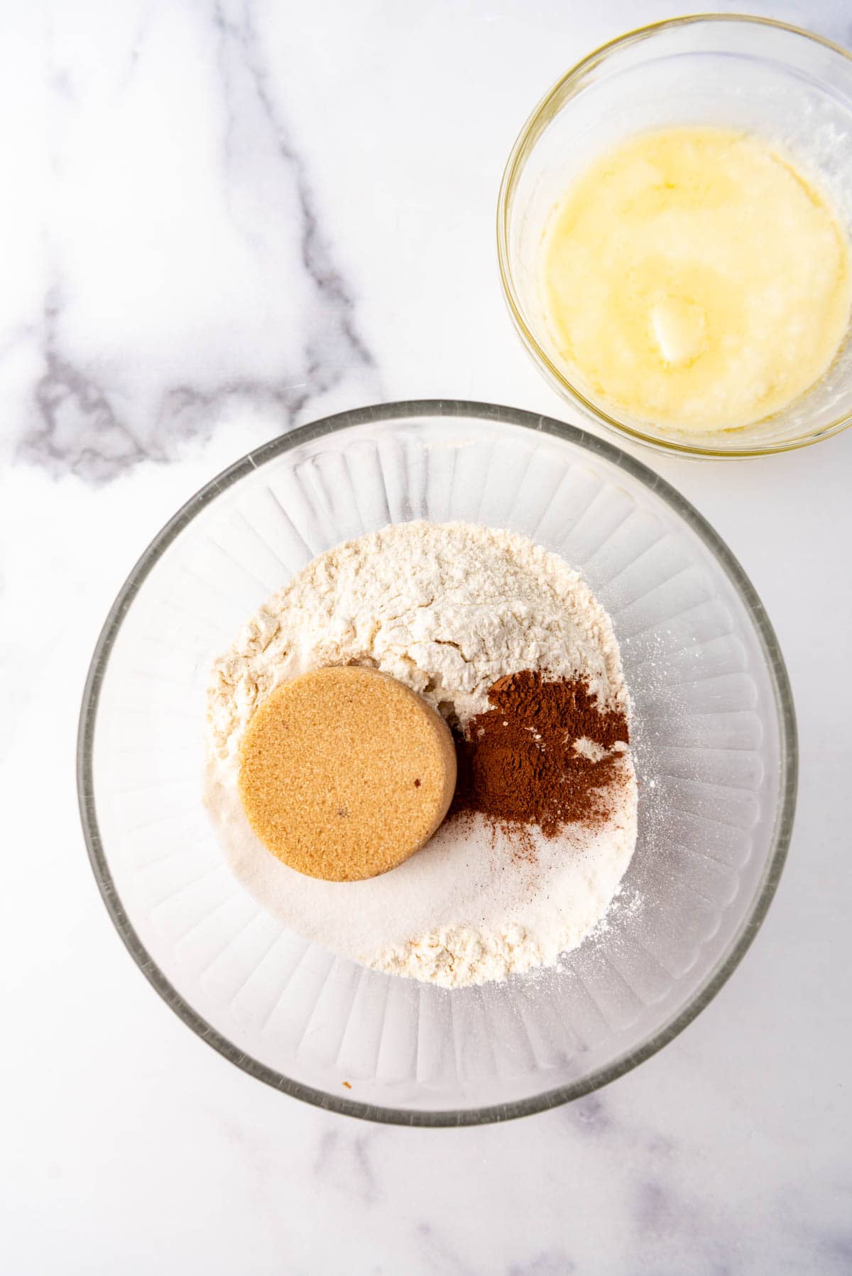 Combining flour, sugar, and cinnamon in a bowl next to a bowl of melted butter.