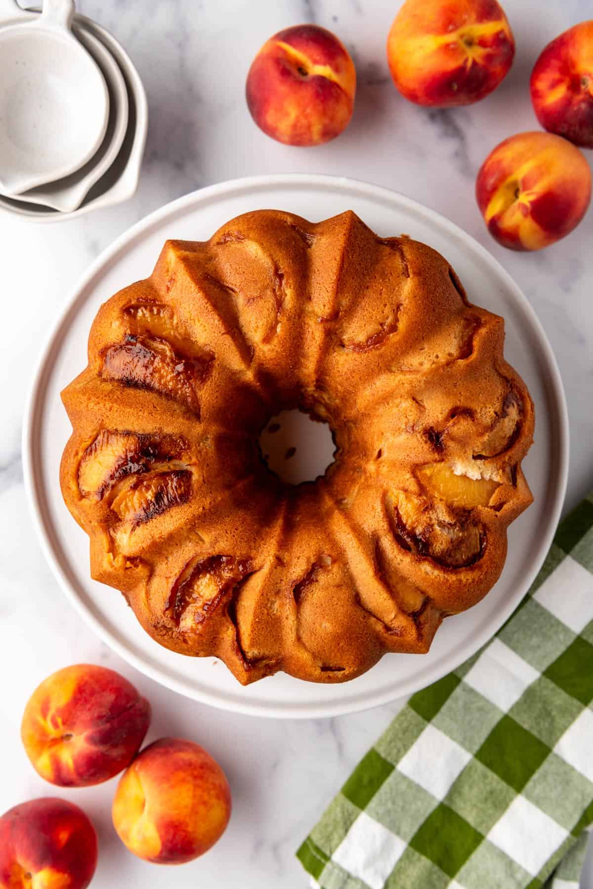 A baked peach cobbler pound cake turned out onto a white cake plate.