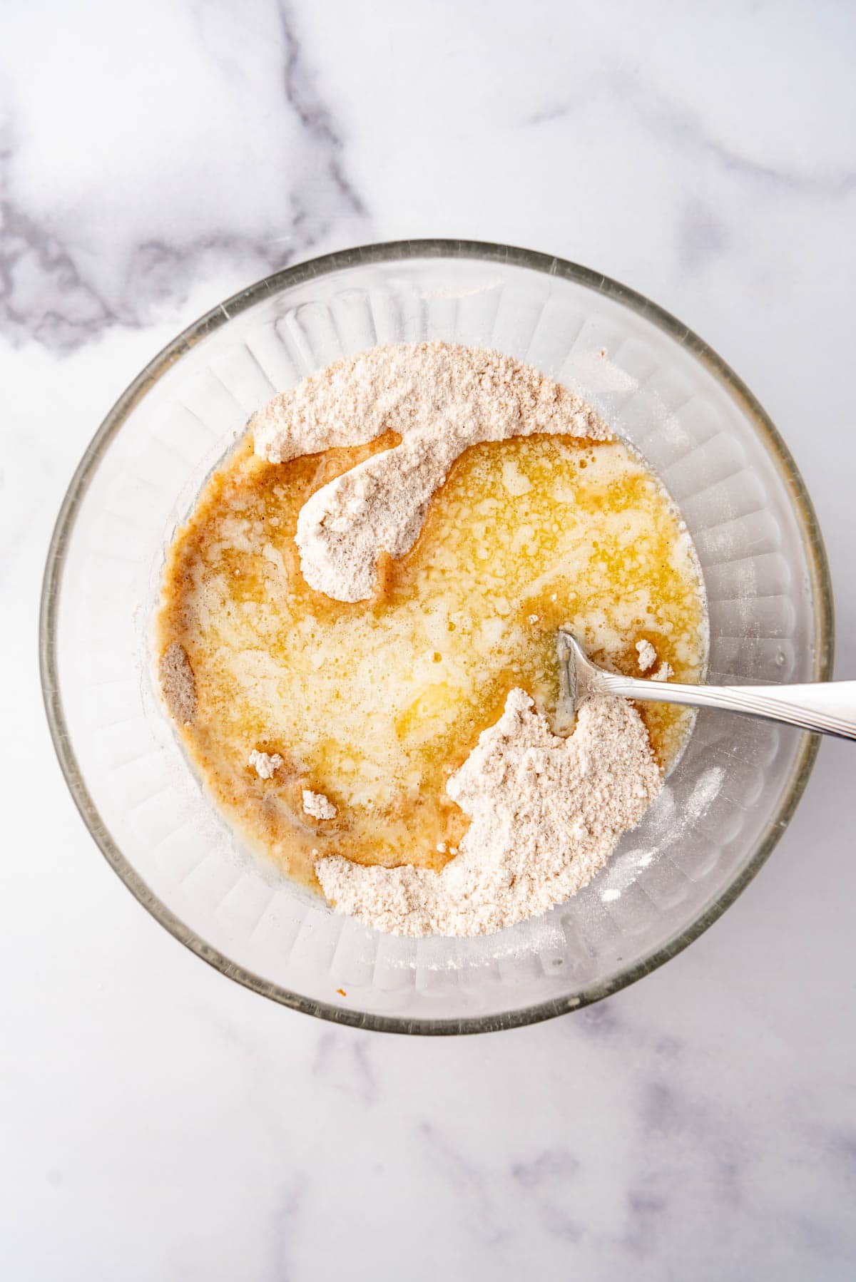 Adding melted butter to dry ingredients to make a crumble topping.