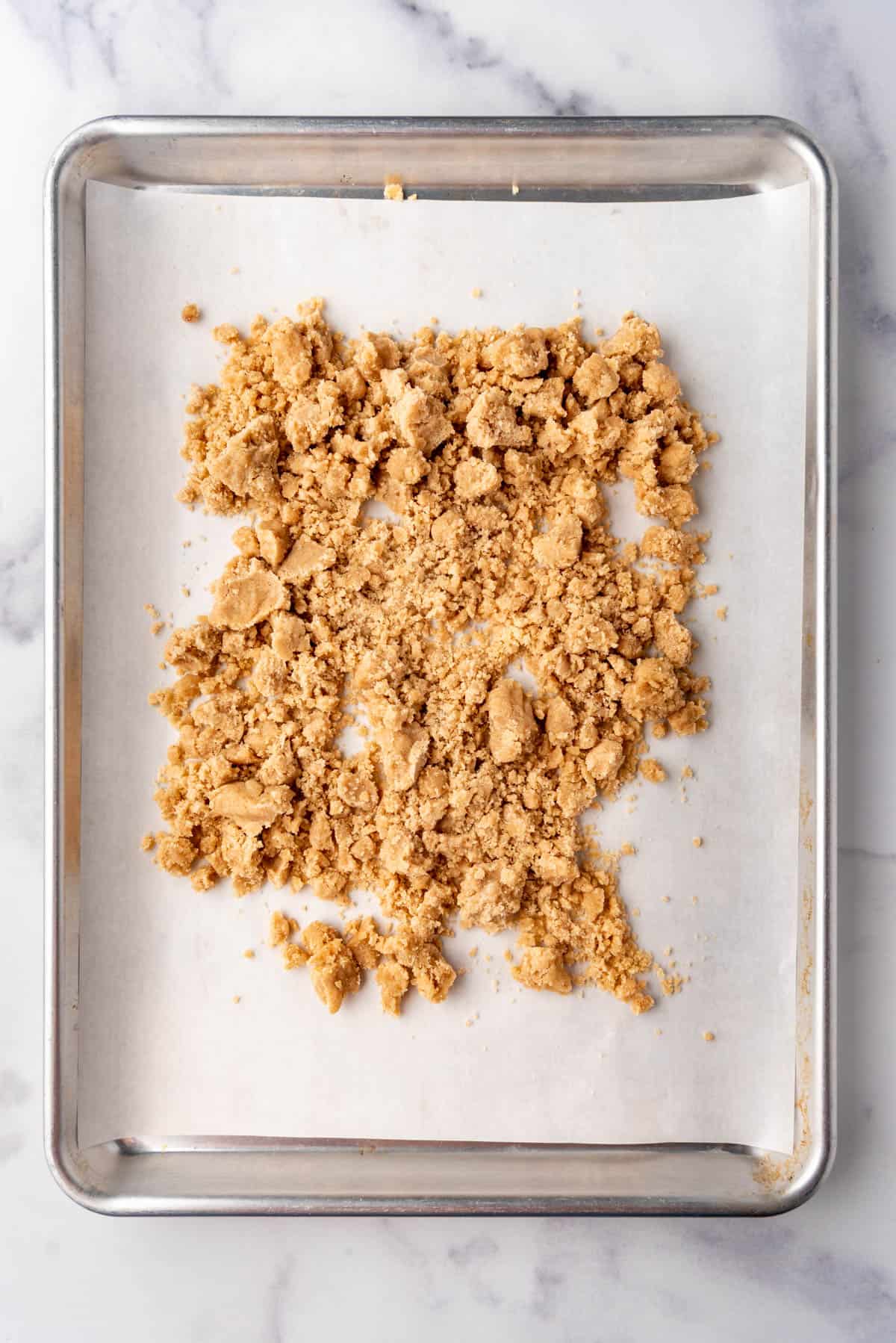 Crumble topping on a baking sheet with parchment paper.