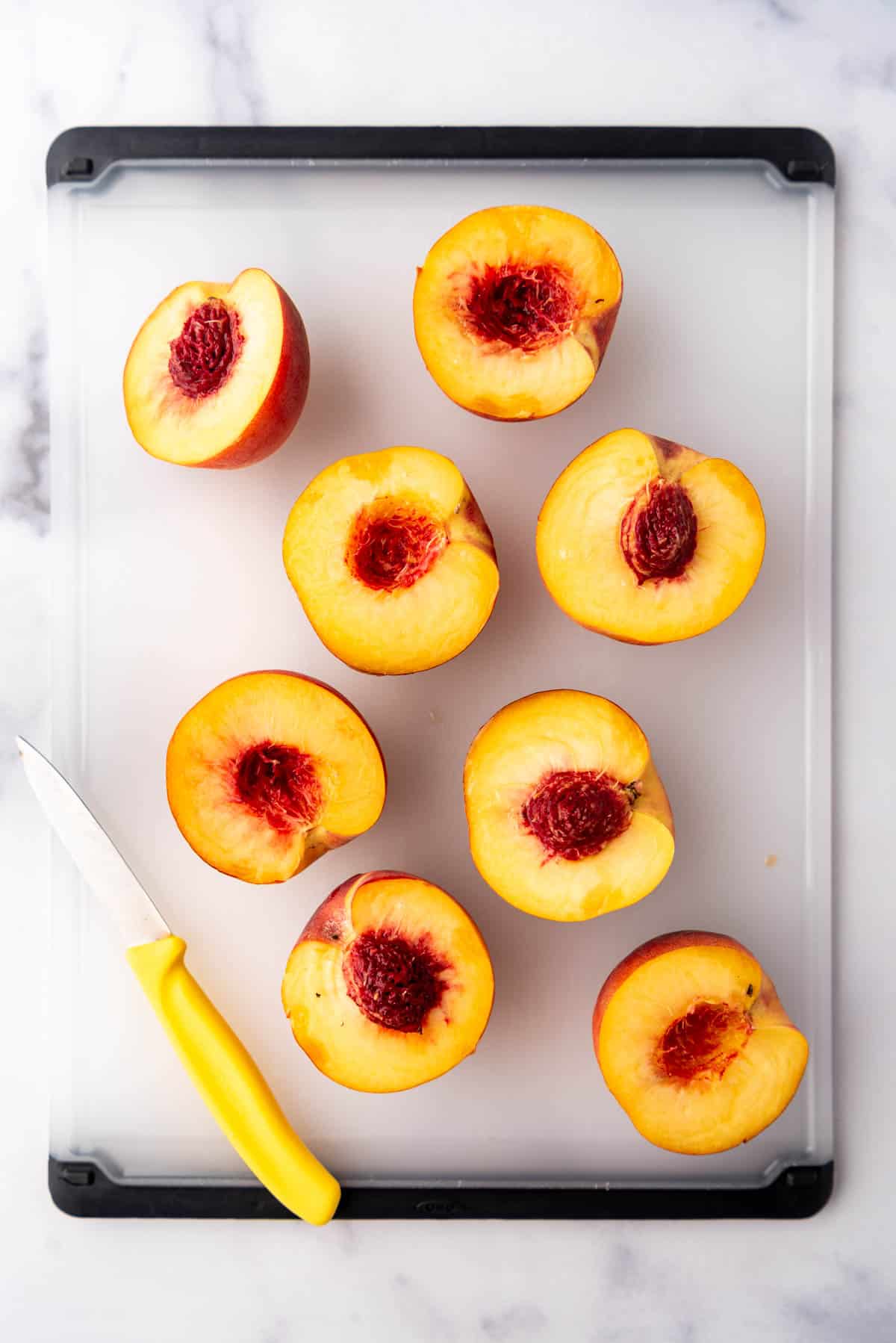 Halved fresh peaches on a cutting board.