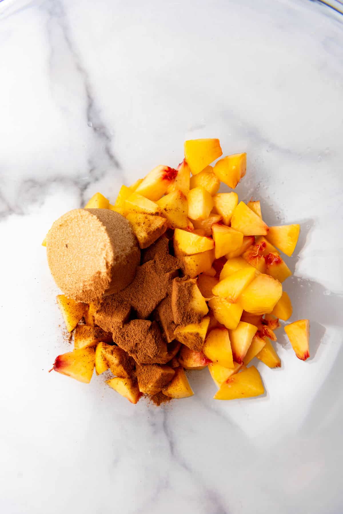 Combining chopped peaches with cinnamon and sugar in a bowl.