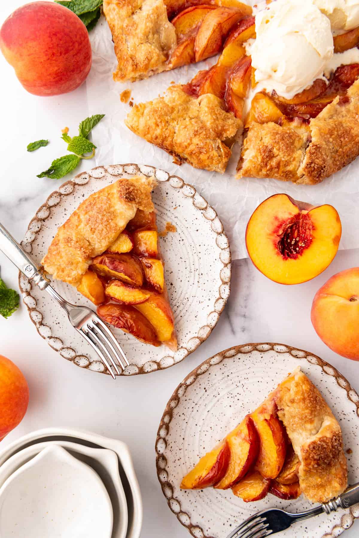 An overhead image of slices of peach galette on plates next to the rest of the dessert.