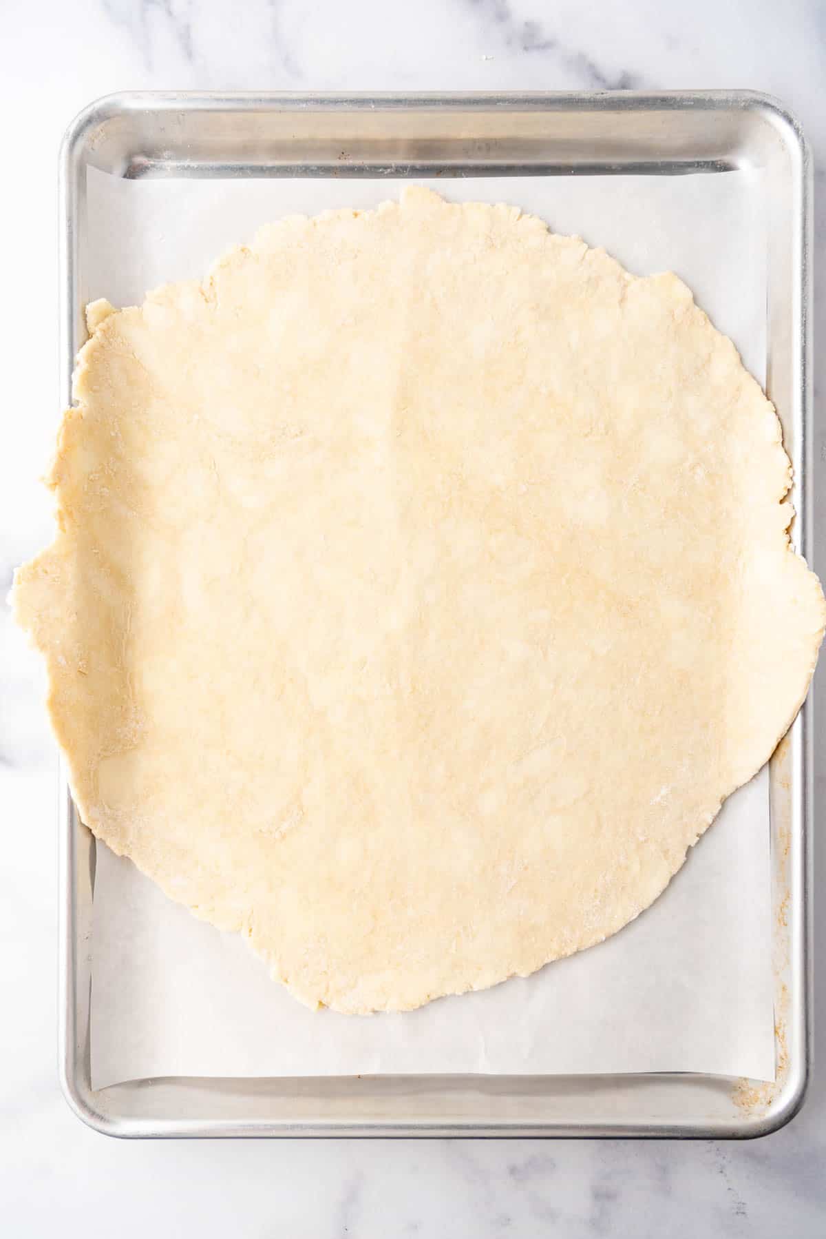 A rolled out all-butter pie crust on a baking sheet.