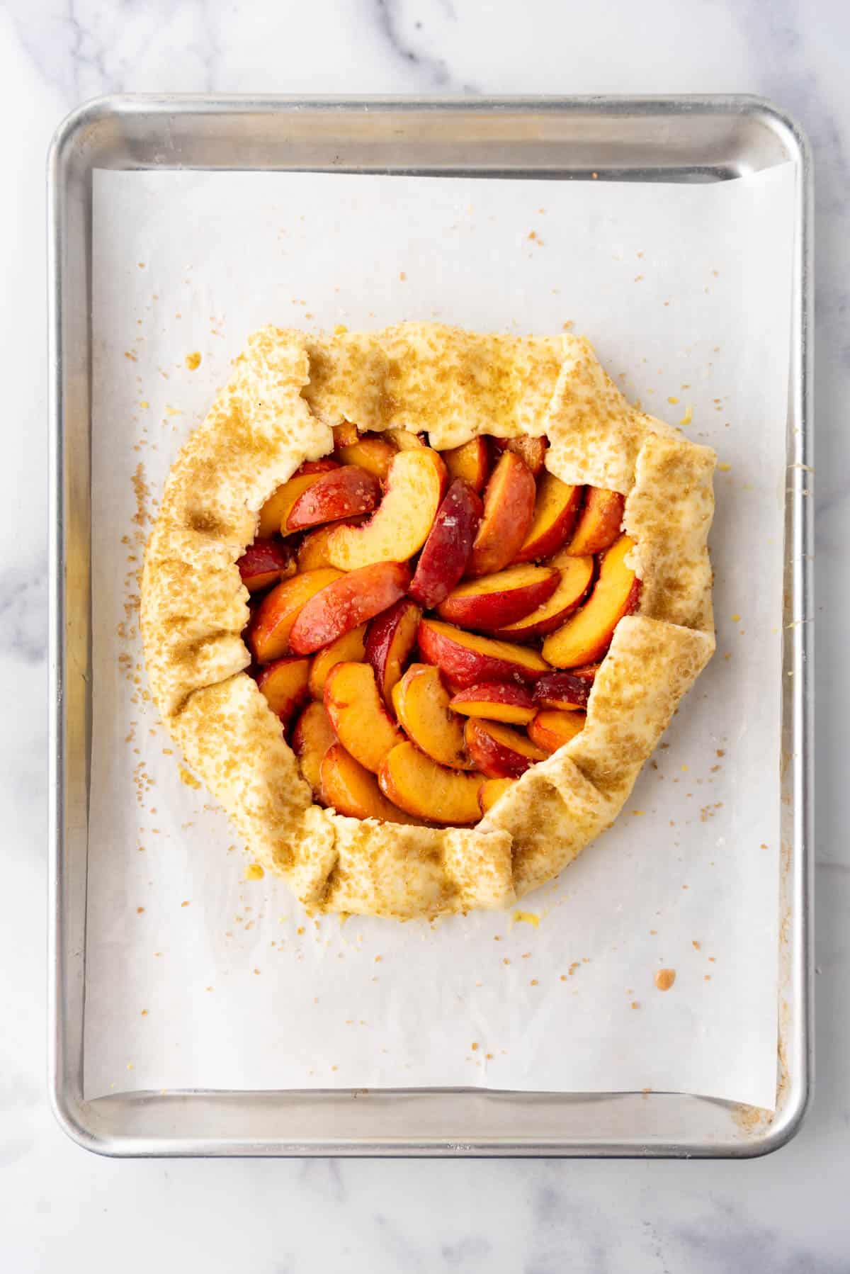 A galette after the edges of the crust have been brushed with egg wash and sprinkled with coarse sanding sugar.