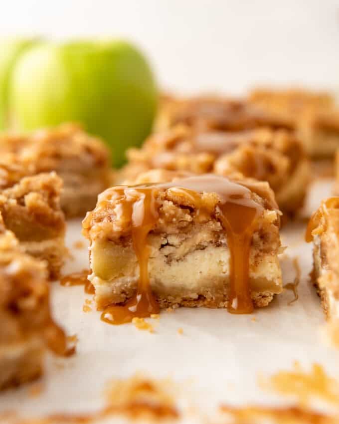 An image of a caramel apple cheesecake bar with caramel dripping down the side.