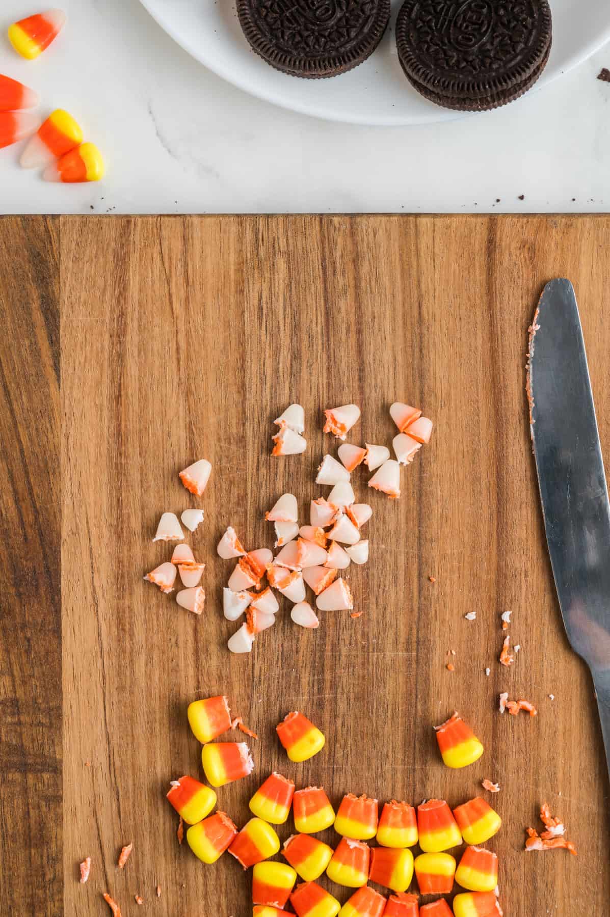 Cutting off the white tips of candy corn on a cutting board.