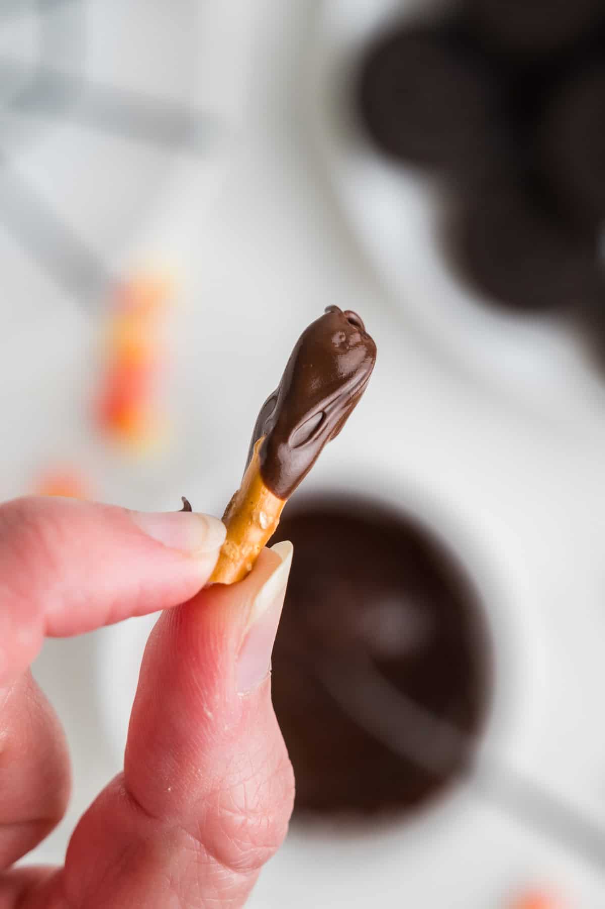 Dipping pretzel sticks in melted chocolate.