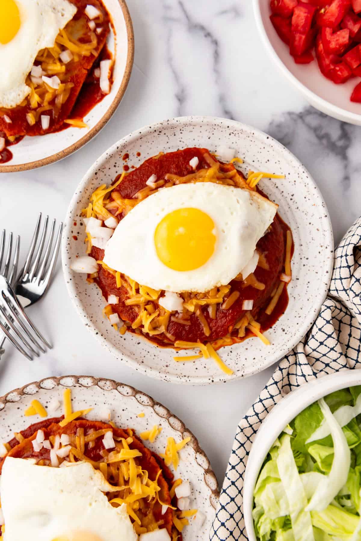 An overhead image of a plate of stacked enchiladas with a fried egg on top.