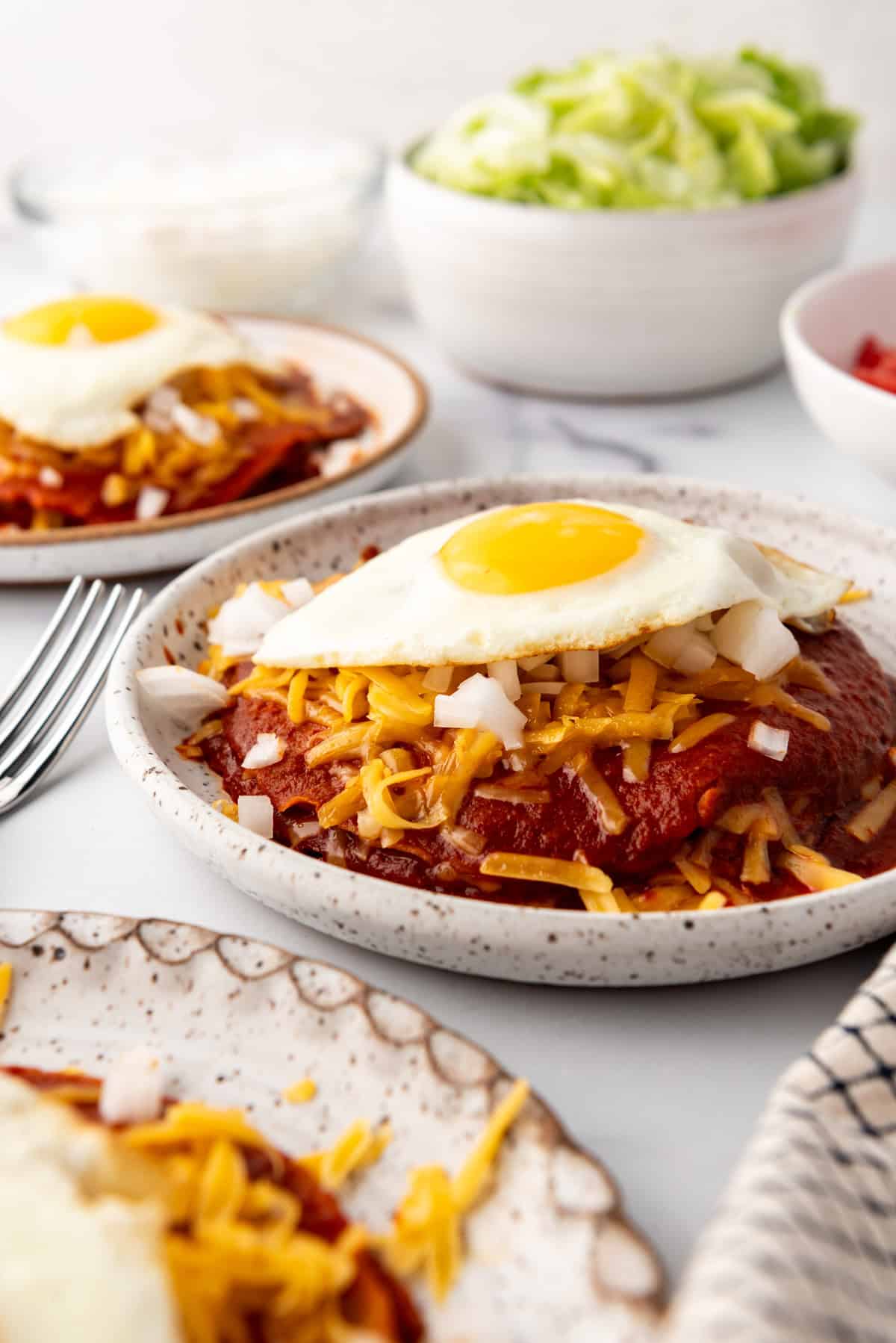 A side view of stacked enchiladas topped with fried eggs.