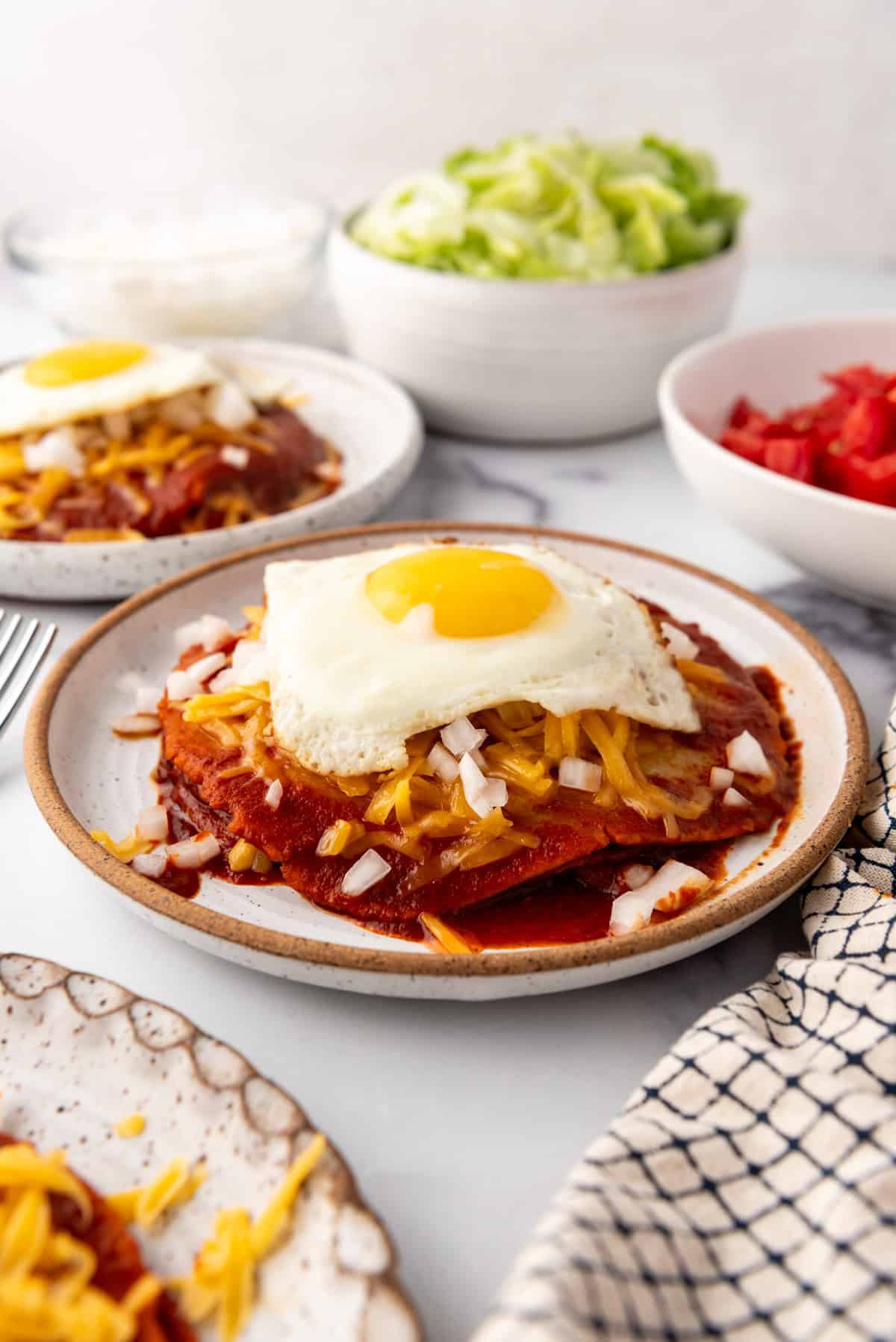 Une image d'enchiladas empilées à la style du Nouveau-Mexique avec un œuf frit sur le dessus.