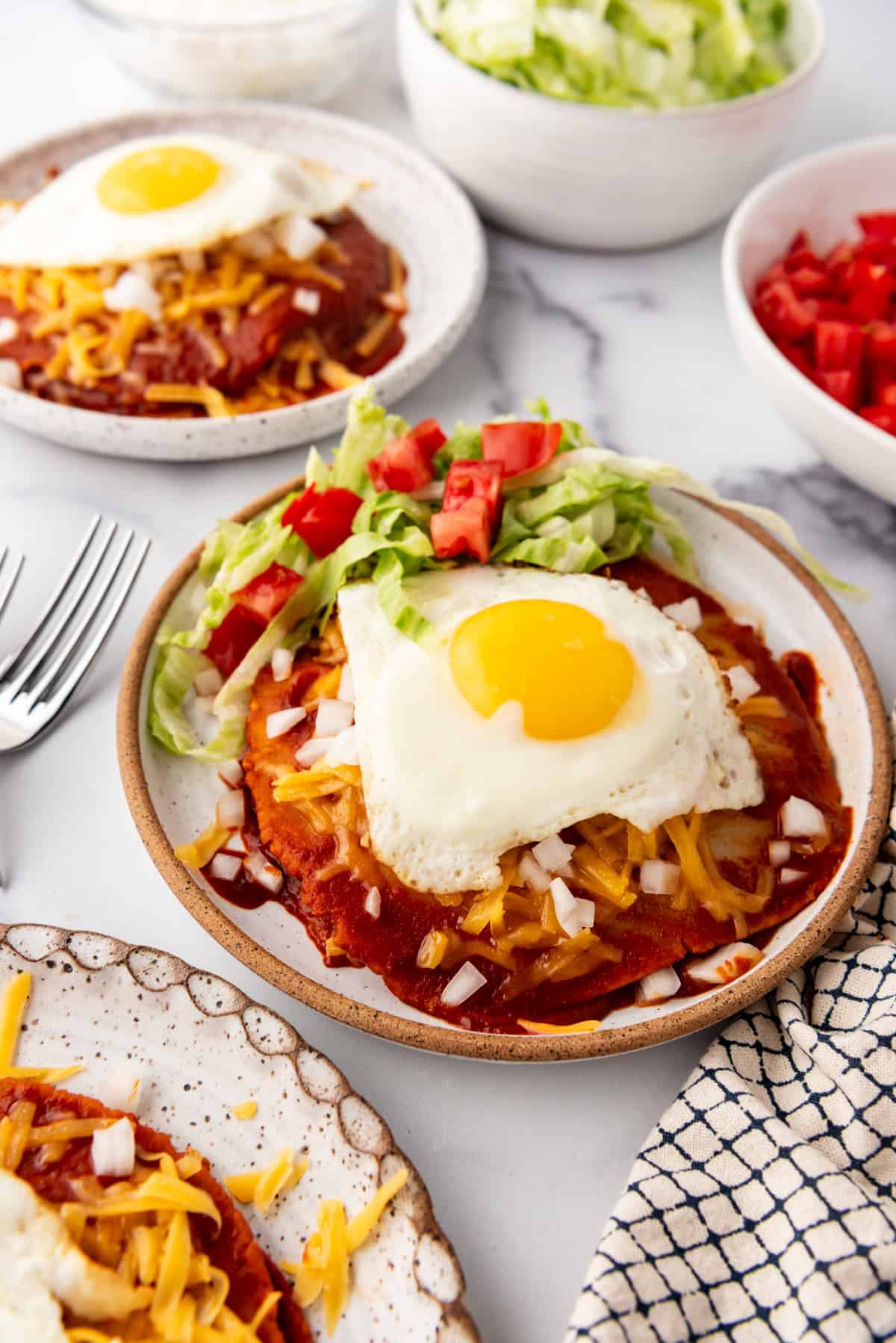 Stacked cheese enchiladas with a fried egg sunny side up on top.