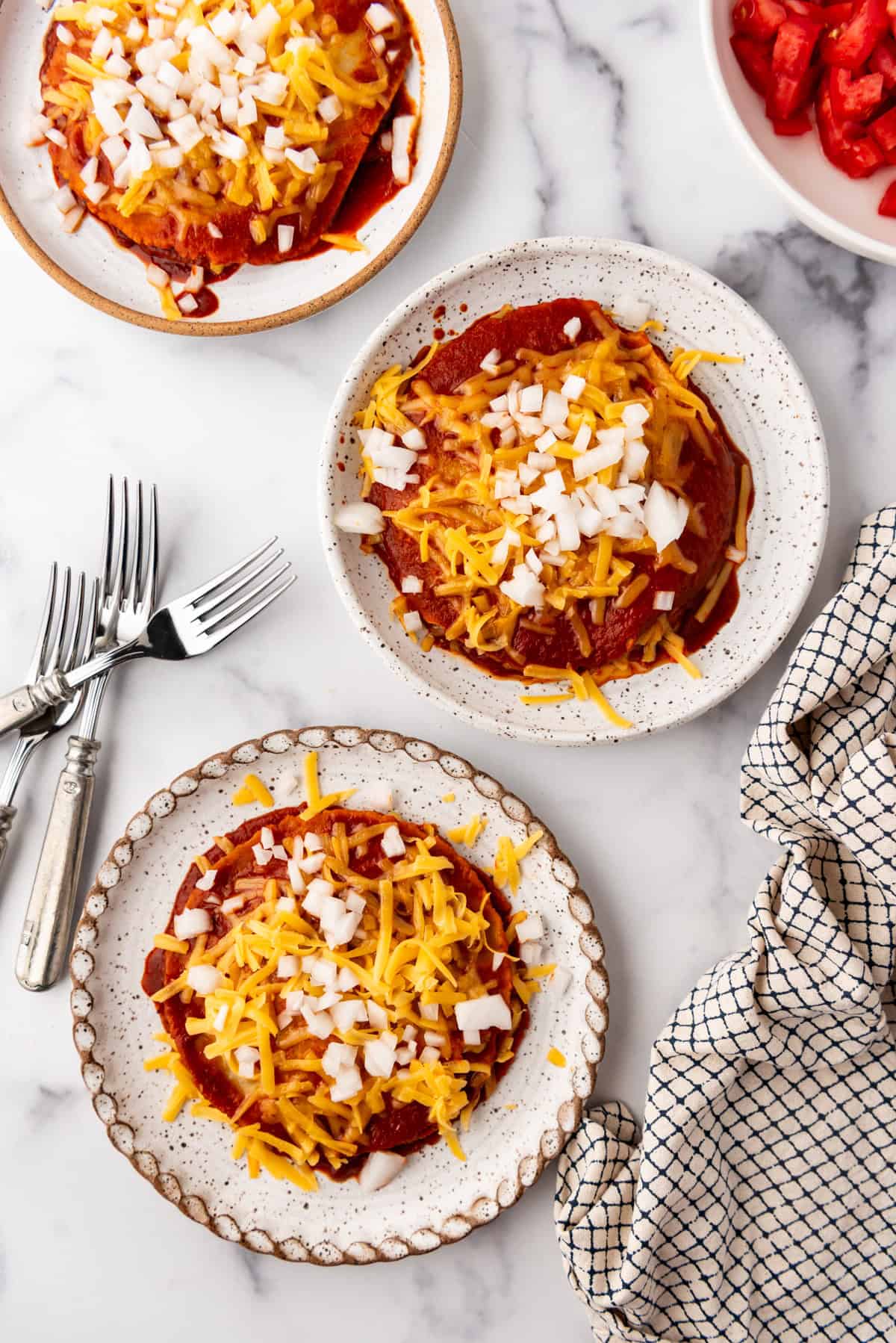 An overhead image of plates of stacked enchiladas, New Mexico-style.